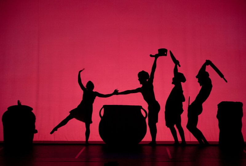 4 dancers in shadow in front of a pink background. A giant clay pot sits between the dancers
